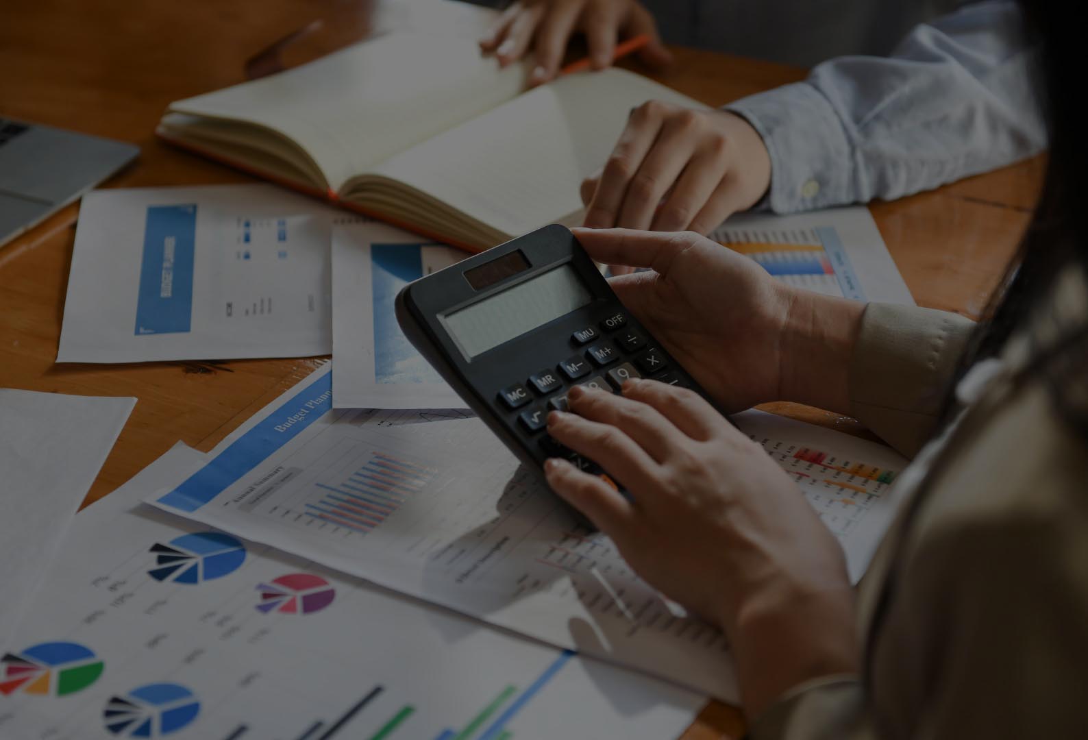 The accounting team is working. She used the calculator and analyze the graphs in office.